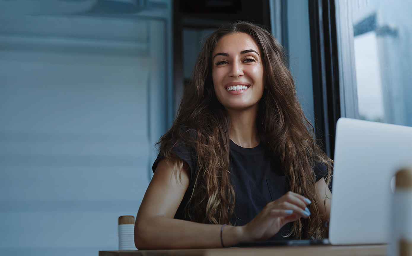 Smiling caucasian woman working on laptop and looking happy. Freelancer using computer, networking at home.